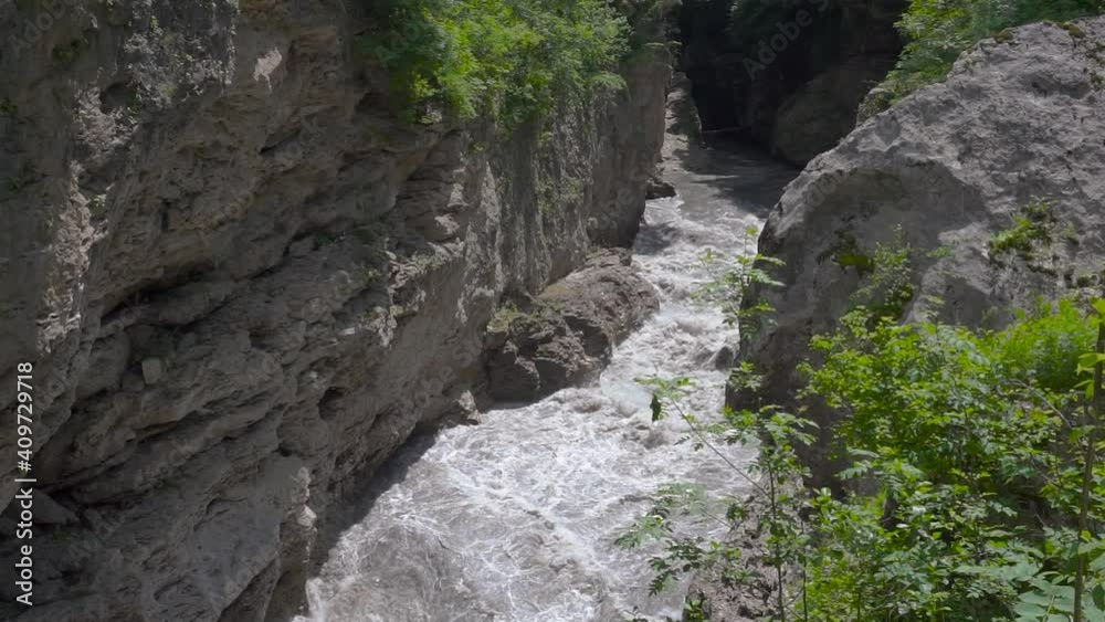 Khadzhokhsky gorge. Narrow part of the gorge Belaya River. Kamennomostsky. on a sunny spring day. The rapid flow of water from the Belaya River continues the destruction of the gorge walls and Khadzhokhsky gorge. Narrow part of the gorge Belaya River. Kamennomostsky. on a sunny spring day. The rapid flow of water from the Belaya River continues the destruction of the gorge walls and
