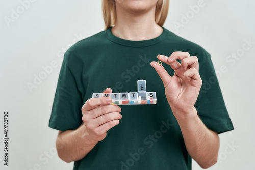 Young man holding week pill organizer