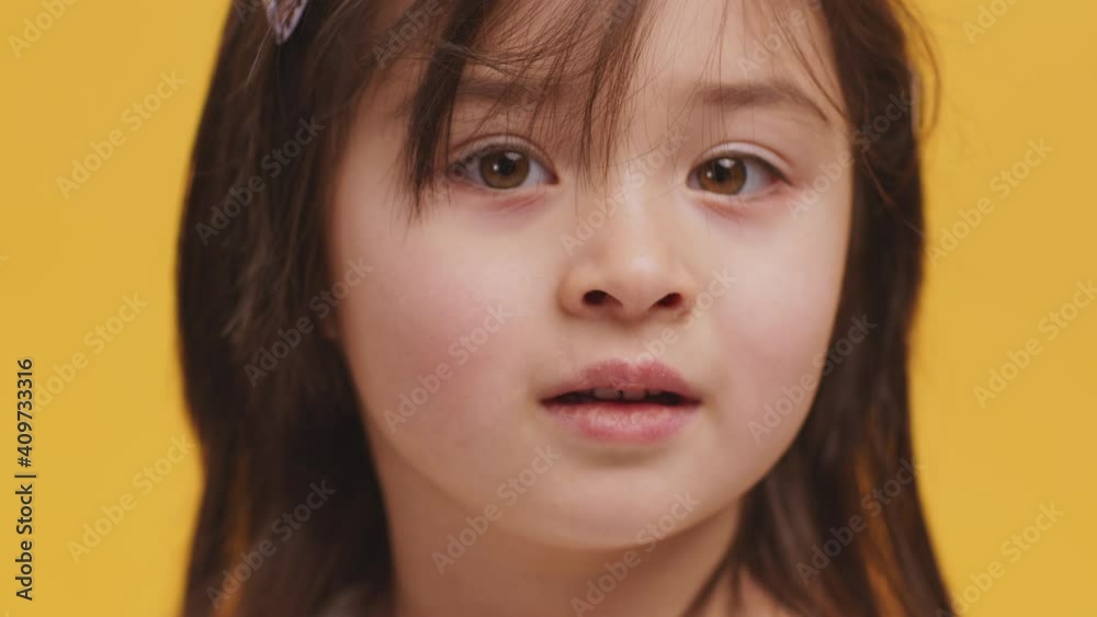 Close up portrait of adorable girl looking at camera, orange studio background Close up portrait of adorable girl looking at camera, orange studio background