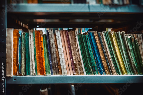Tableau sur toile books in soft color covers on shelves in the archive blurred image, library