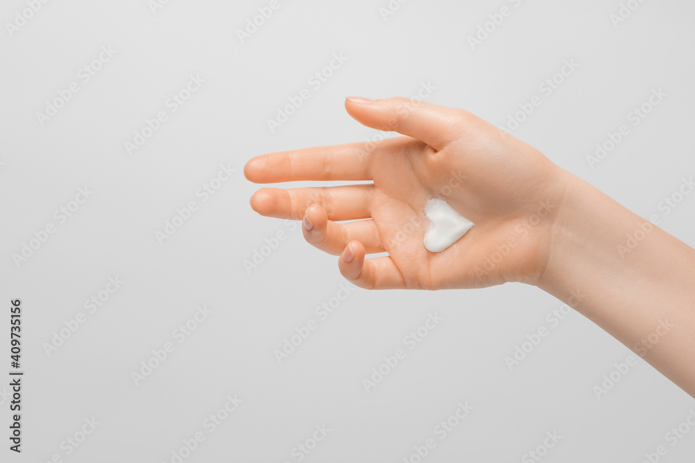 Naklejka premium A thick light heart-shaped cream on a woman's hand. Groomed hands, natural short nails, on a light background.