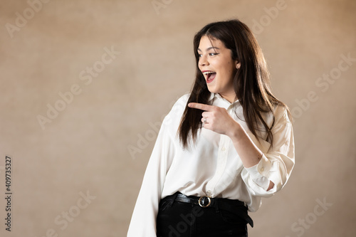 Foto mujer joven morena caucasica señalando a un lado y sonriendo