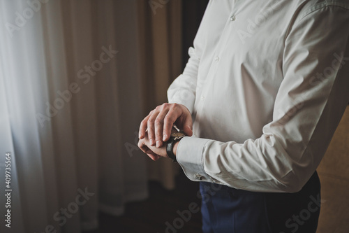 Mens hands are holding on to the wristwatch on their hand 2591.