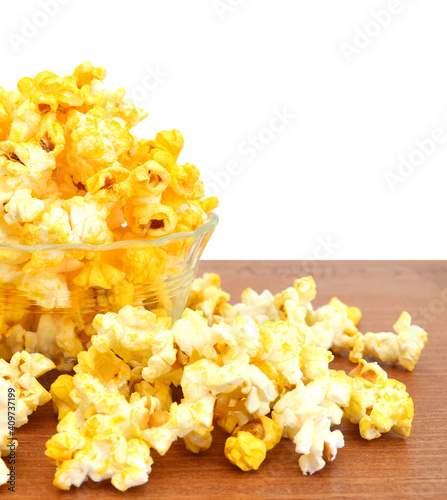 Glass bowl of fresh popped popcorn isolatedi in wooden board