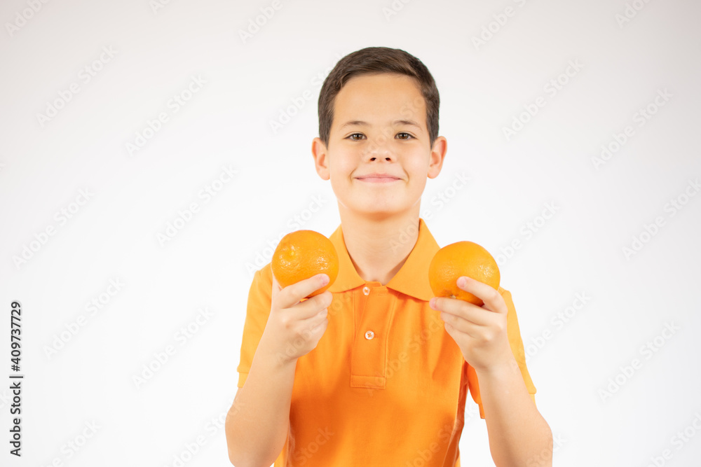 Beautiful young boy holds two oranges in his hands and smiles on a white background. Beautiful young boy holds two oranges in his hands and smiles on a white background.