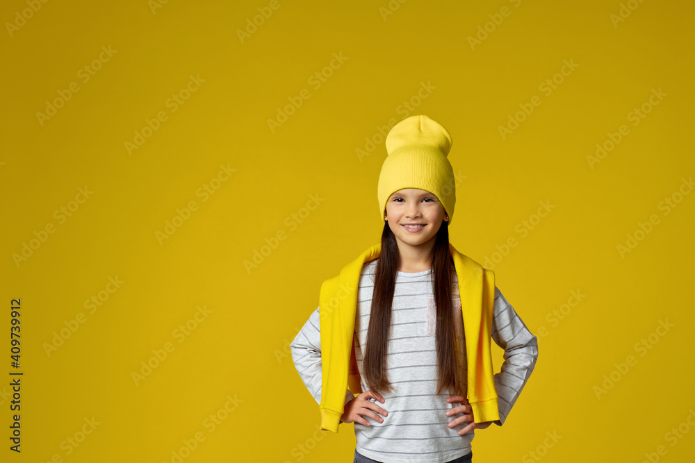 fashionable little child girl in yellow hat and sweatshirt posing on yellow studio background. copy space fashionable little child girl in yellow hat and sweatshirt posing on yellow studio background. copy space