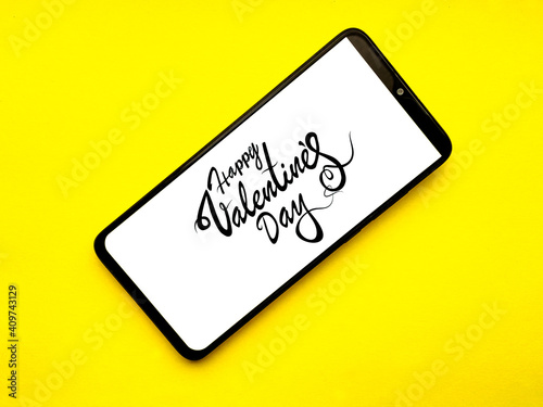 Phone with Valentine's happy day inscription on a yellow background