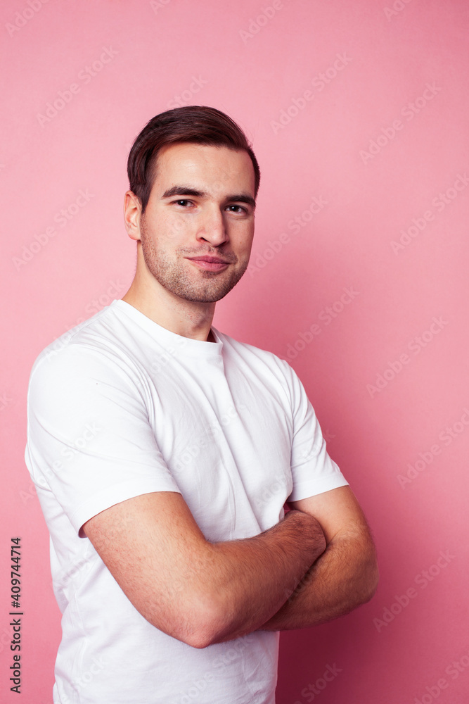 young caucasian guy in white t-shirt posing cheerful on pink background, lifestyle people concept