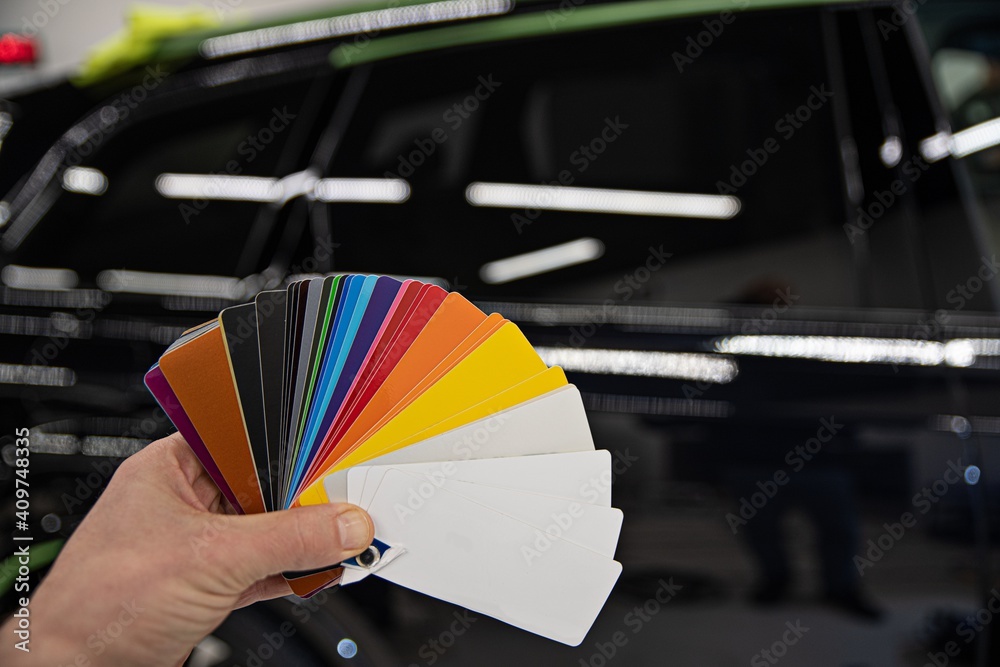 Man choosing color of his car with color sampler. Car foil wrapping colors picker