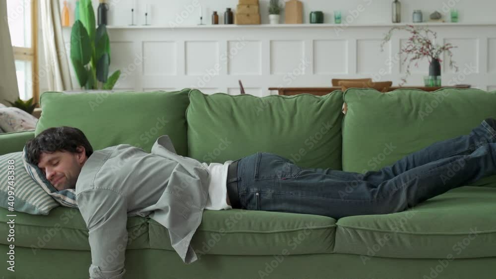 Exhausted young man came home after work flopped down on sofa Exhausted young man came home after work flopped down on sofa