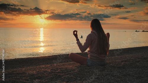 Lady having meditation over the sea before sunset. Silence and relaxation concept.