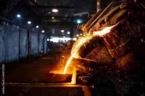 Casting, melting, molding and foundry. Bucket with hot molten iron pouring into the mold. Industrial steel production.