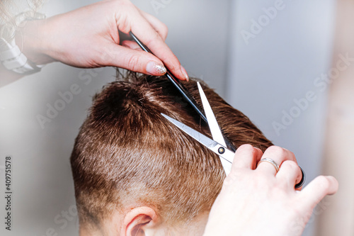 Mommy cuts hair with scissors and combs her son in the bathroom.