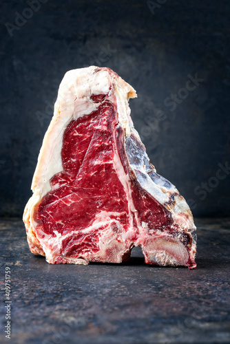 Raw dry aged wagyu t-bone beef steak offered as close-up on rustic board with copy space photo