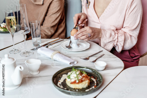 A woman peels an egg for breakfast in a restaurant. Selective Focus