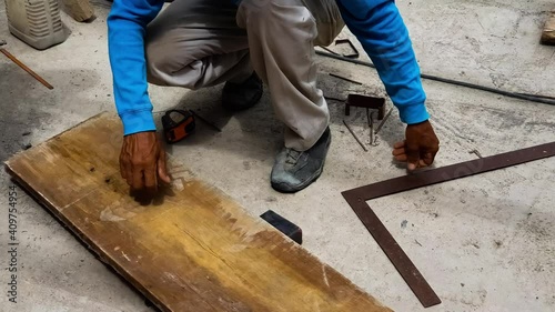 Man makes a straight line with a metal ruler and a pencil