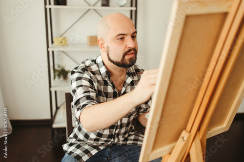 Art, creativity, professional occupation. Artist working in home studio. Man painting with watercolor at easel. Creative leisure and remote work concept