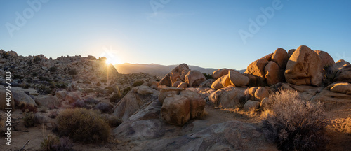 Last light of sunset behind rocks and boulders in panoramic view of desert landscape on a sunny January day with clear blue sky in Yucca Valley, California near Joshua Tree National Park