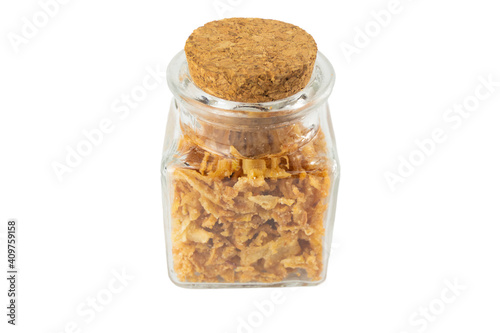 Crispy carmelized fried onion flakes in a glass jar isolated on white background. Spices and food ingredients.