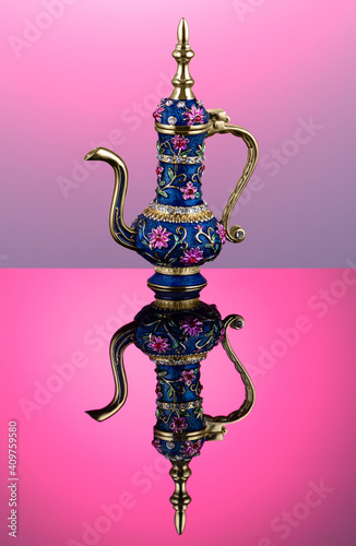 Ornamented engraved oriental teapot with a long golden spout and a lid