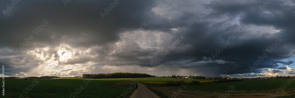 Panorama of rural landscape at wild changing stormy weather condition with rain and sun
