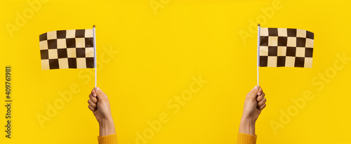 checkered flag in hands over yellow background, panoramic image photo