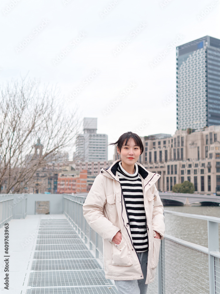 Portrait of Chinese young woman with Shanghai landmarks background in winter day.