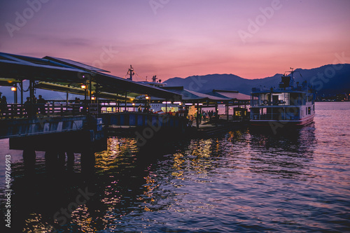 Amazing view of dock, ferry boat and sunset over the sea with mountains in the horizont from the Miyajima Island, Japan