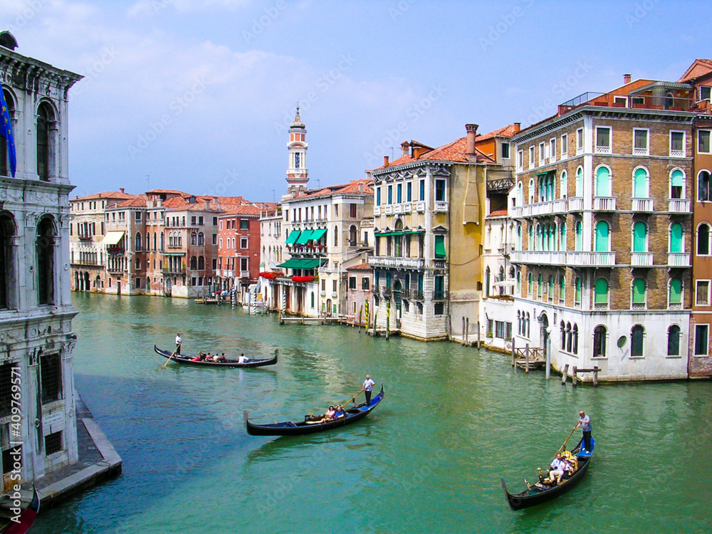 Venice canal with three gondolas and buildings overlooking the water.