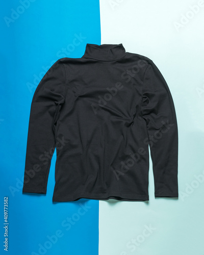 Men's black sweater with long sleeves on a two-tone background.