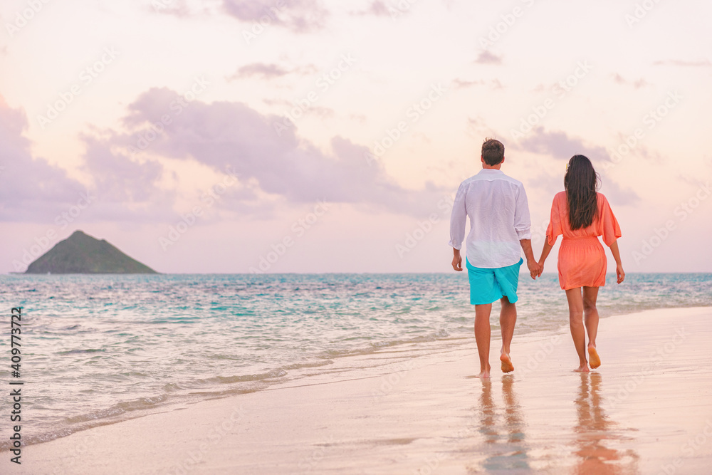 Couple beach vacation travel happy together romantic honeymoon in Lanikai, Oahu, Hawaii. Woman in dress, man wearing shirt. Beautiful sunset stroll lovers in love.
