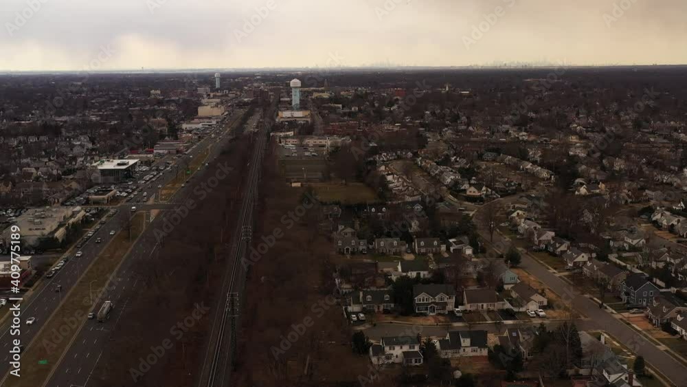 An aerial view of an empty railroad tracks. Residential homes are on the right, a highway, businesses on the left. The drone camera dolly in, tilt up over the tracks as it flurries on Long Island. An aerial view of an empty railroad tracks. Residential homes are on the right, a highway, businesses on the left. The drone camera dolly in, tilt up over the tracks as it flurries on Long Island.