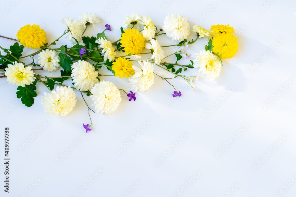 White and yellow chrysanthemums with wildflowers on a white background with copy space