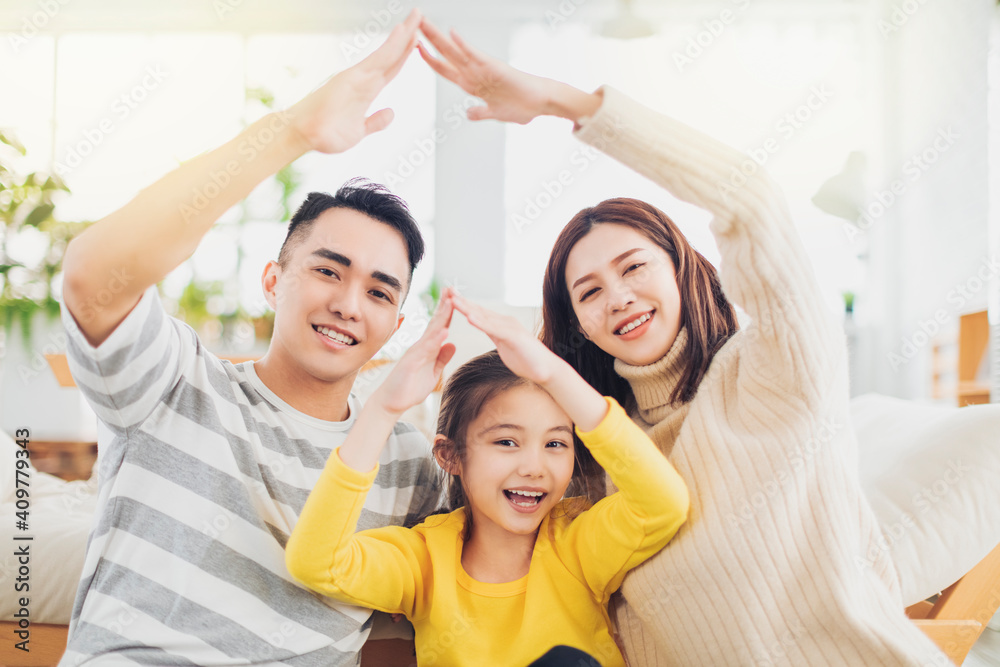 Happy asian family forming house roof with their hands at home Happy asian family forming house roof with their hands at home