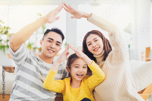 Happy asian family forming house roof with their hands at home