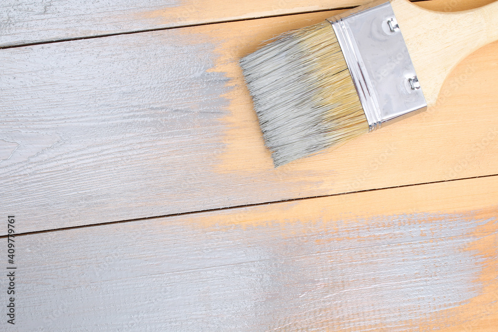 Brush with can paint in hand. A man paints wooden boards in a gray paint brush. Brush with can paint in hand. A man paints wooden boards in a gray paint brush.