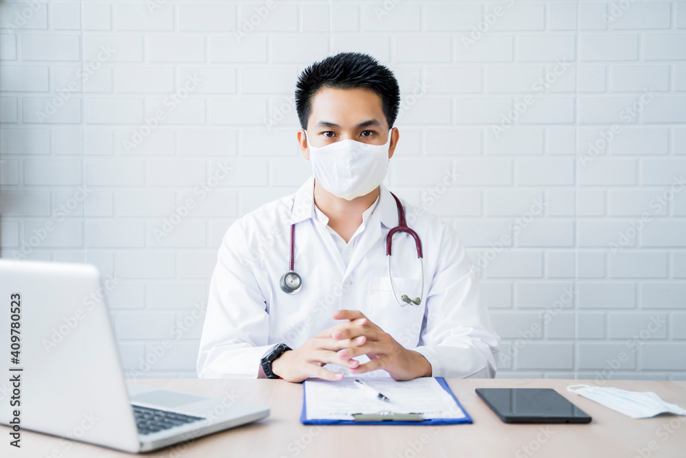 Asian Medical healthcare clinic male doctor e wearing face mask examining diagnosing patient clipboard writing, working at home modern office using smart tablet computer laptop information technology Asian Medical healthcare clinic male doctor e wearing face mask examining diagnosing patient clipboard writing, working at home modern office using smart tablet computer laptop information technology