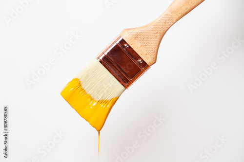 Fototapeta Naklejka Na Ścianę i Meble -  Close-up paintbrush with liquid yellow paint drips off the brush