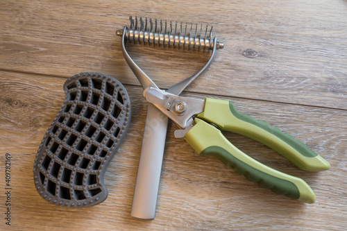 Dog grooming and bathing tools close up. 2 sided undercoat rake, nail clipper, rubber brush.