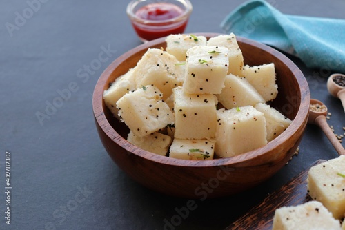 Indian popular Gujrati breakfast dish White Dhokla, Khatta Dhokla, Rice and Urad Dal Khaman. Also known as Instant Rava Dhokla. served with ketchup over black background. copy space. photo
