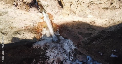 a breathtaking waterfall in winter icy stream in sunset and shadow on the scenery landscape view. icicle hanging around the cliff and cold white water splashes on the ground. photo