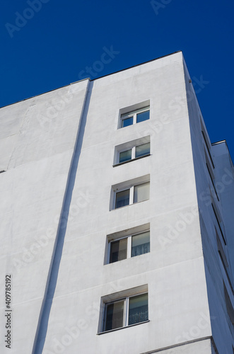 A fragment of a tall residential building against a clear blue sky.