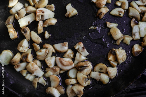 Raw mushrooms are fried in a pan.