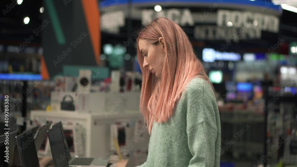 Woman chooses a laptop in a device store Woman chooses a laptop in a device store