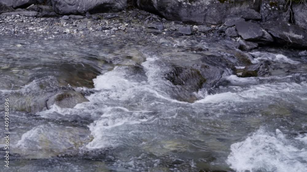 Zoom out of a fast moving river during winter in slow motion Zoom out of a fast moving river during winter in slow motion