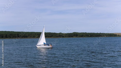 Low angle shot of sailboat out to sea heading down coast. Aerial. photo