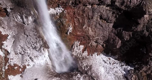 ice waterfall flow down heavily from a cliff on a snow covered ground in wild nature. snow like a salt in mountain. highlands of Alamut valley in Iran. travel to countryside for hiking in outdoor. photo