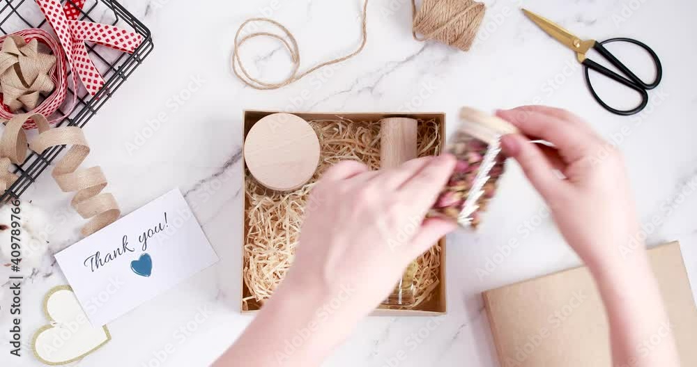 Preparing care package, seasonal gift box with tea, self care products, essential oil and thank you card. Personalized eco friendly basket for friends and family