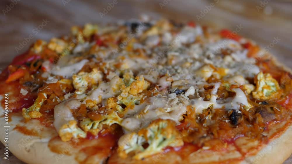 Hand serving vegan pizza with vegetables and vegan cheese on the wooden table. Healthy vegan lifestyle Hand serving vegan pizza with vegetables and vegan cheese on the wooden table. Healthy vegan lifestyle