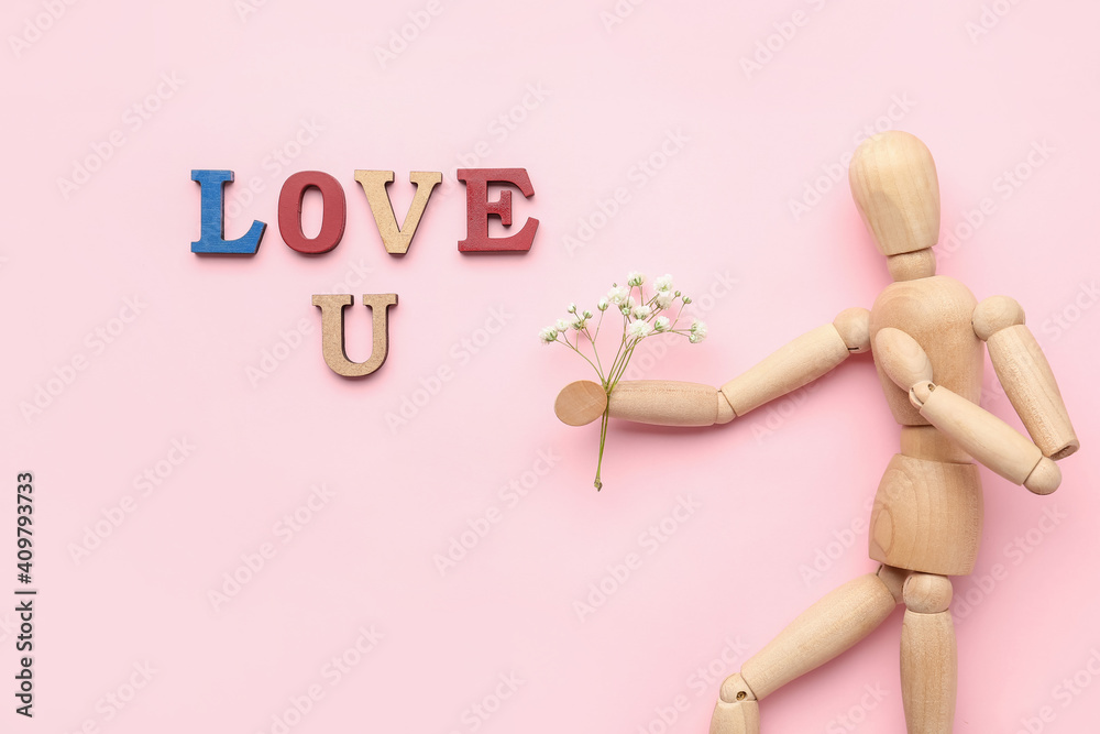 Wooden mannequin with flowers and words LOVE U on color background Wooden mannequin with flowers and words LOVE U on color background